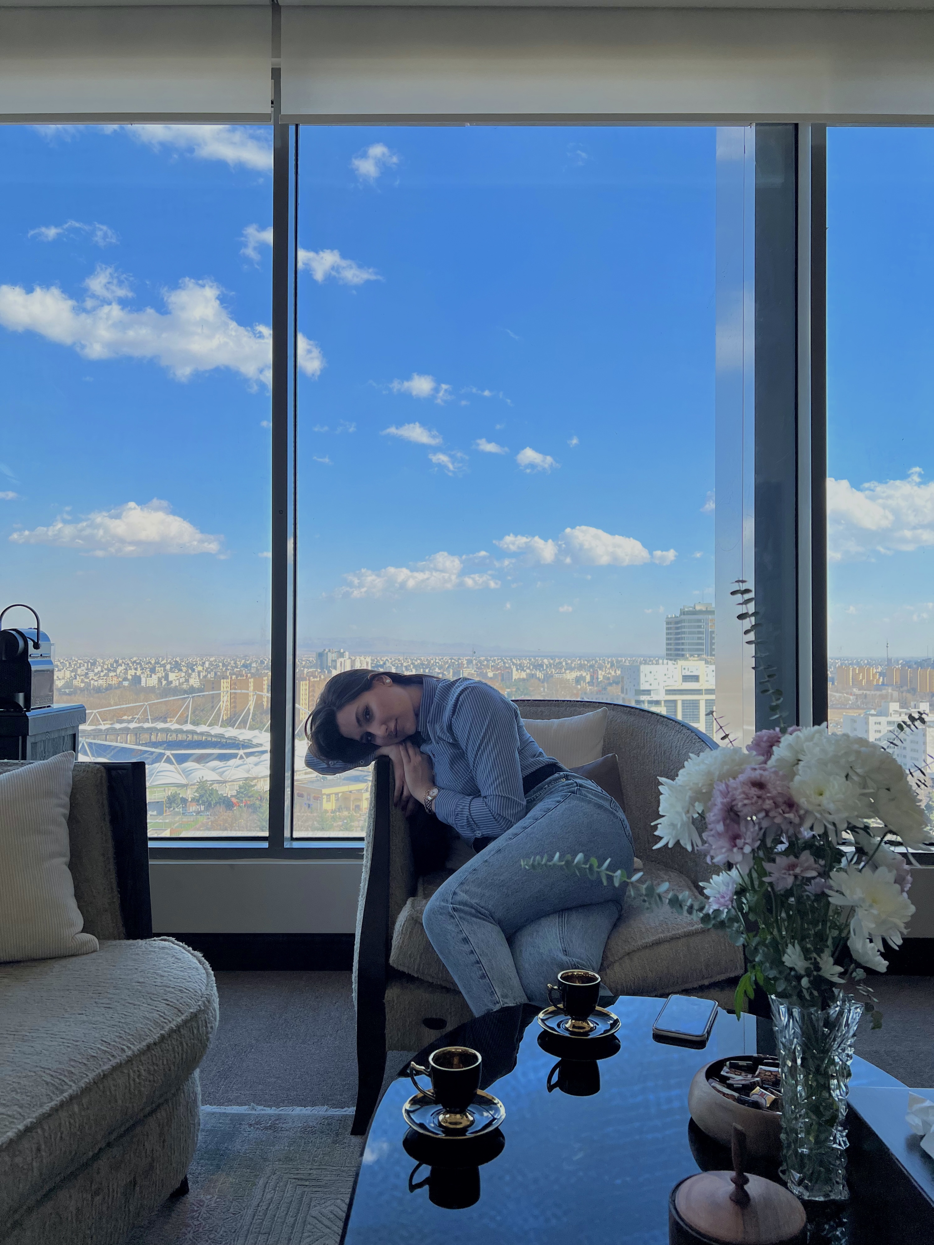 Negar beside a window overlooking the city under a blue sky